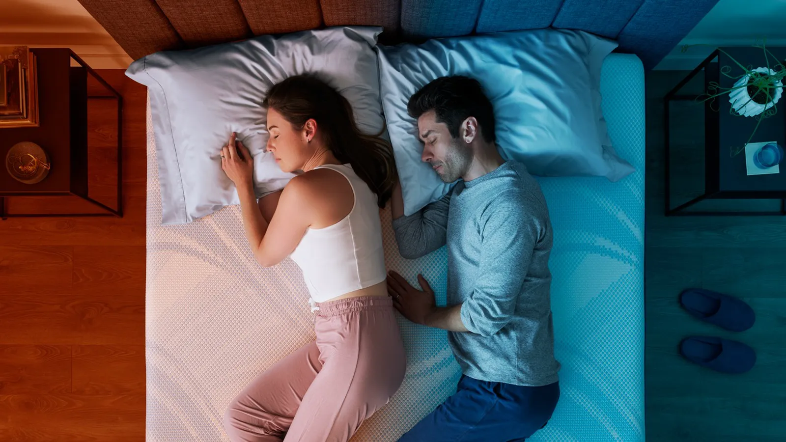 A couple asleep seen from above on a dual-zone bed, her side lit warm and his side lit cool