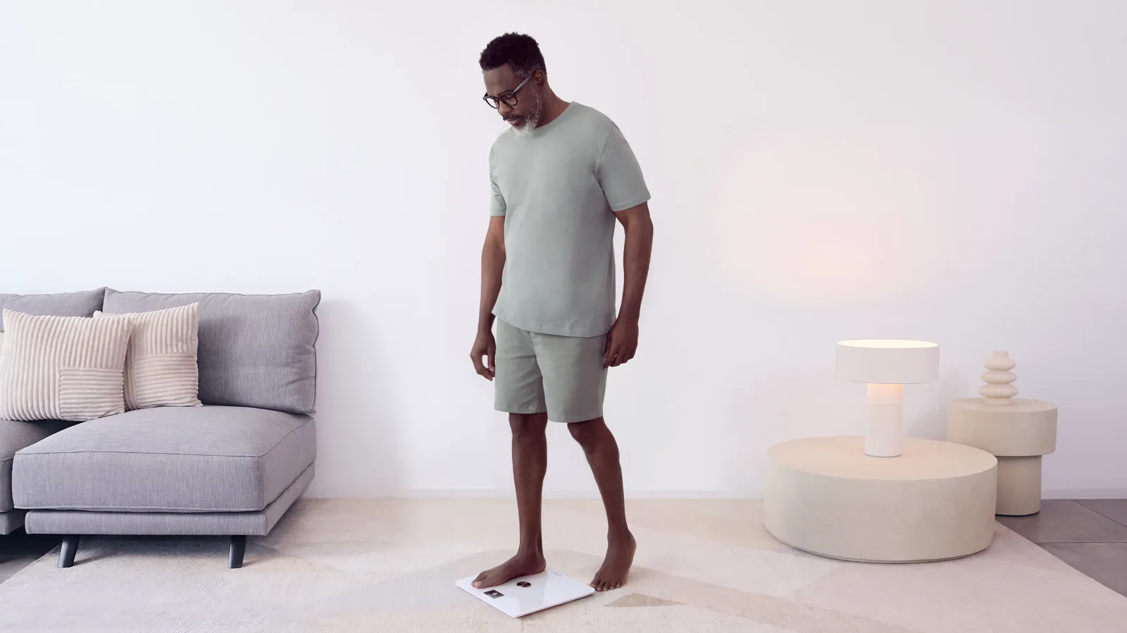 A man stepping onto a Withings smart scale in a bright living room